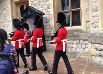 red coated British guards marching away; black hats and black pants